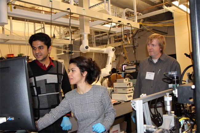 Bootcamp student and Bridgewater State University professor, Elif Demirbas, learning how to perform grating coupling from a fiber to a chip with instruction from Robin Singh, while Phillip Wilcox, an engineer from U.S. Army CCDC, looks on. Courtesy of MIT.