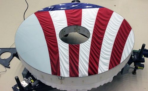 The Roman Space Telescope’s primary mirror reflects an American flag. Its surface is figured to a level hundreds of times finer than a typical household mirror. Courtesy of L3Harris Technologies.