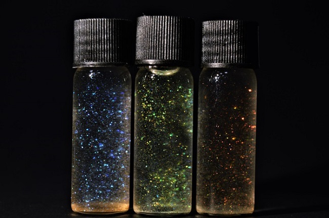 The photograph shows three vials containing an ensemble of photonic CNC particles dispersed in three different solvents: water; water: ethanol; and ethanol. The particles are the same in the three vials. The color difference between the three vials results from the ability of water to swell the structure of the particles. Higher water content means greater swelling of the cholesteric structures and a redshift of the color of the particles. Courtesy of Benjamin Droguet.