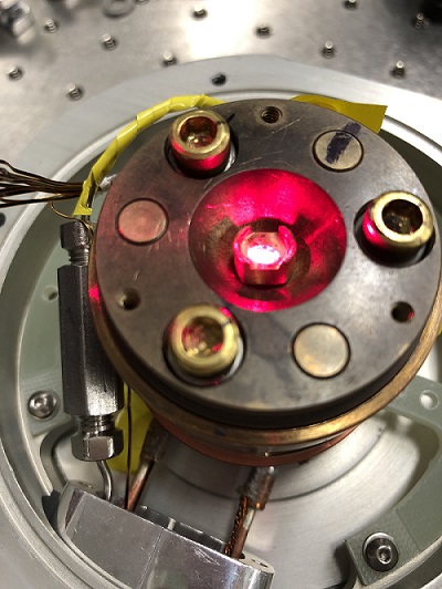 A strong laser is seen illuminating a material in a low-temperature chamber. The laser is being used to change the material's degree of transparency. Courtesy of David Hsieh Laboratory, Caltech.