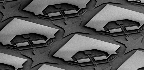 Partial SEM image of the switch matrix: The whole structure patterned in the top silicon layer by dry etching seems to “float” as the oxide is removed. Each matrix unit contains an electrostatic comb drive that can selectively move portions of the waveguides to establish a desired light path from one of the 32 input ports to one of the 32 output ports. Courtesy of SPIE via Han et al.