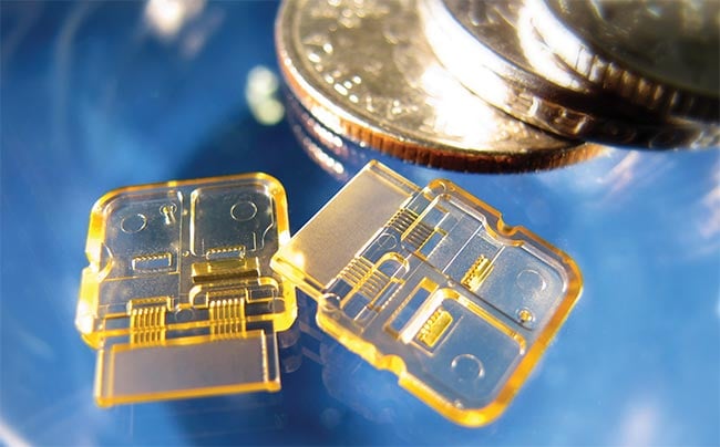 An example of micropolymer optics. These parts, molded out of Ultem (polyetherimide), are part of a complex datacom connector. The geometry includes 12 Ø 250-µm lenses with a ±2-µm positional tolerance. The parts also include V-groove alignment features and a turning mirror that must also meet the exacting standards of the design. Courtesy of Accumold.