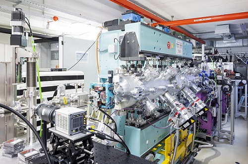 German-French research team builds free-electron laser at the Helmholtz-Zentrum Dresden-Rossendorf (HZDR) driven by particles from a plasma accelerator—and generates well-controllable laser flashes for the first time with this still young technology. In the foreground, the beam line framed by a light-blue magnet arrangement, the undulator; in the background, the metallic beam chamber for the high-power laser DRACO at HZDR. Courtesy of HZDR.