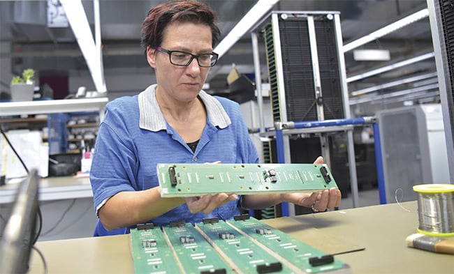 An operator at DICA Electronics inspects a printed circuit board. The operator’s early decisions on possible defects help train and fine-tune the AI model. Courtesy of Pleora Technologies.