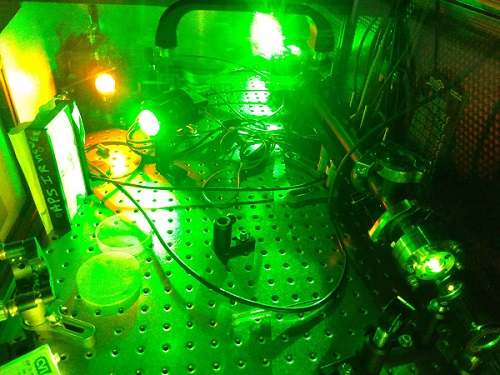 Shooting a green laser through a tube filled with a particular ionic liquid (right side of photo) can easily convert the green laser light to orange (upper left) &mdash; a long-sought color for medical applications. The method can be tailored for different color shifts by choosing different ionic liquids. Courtesy of Brookhaven National Laboratory.