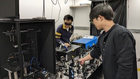 Postodoctoral scholar Haomin Wang (left) and graduate student Dongkwan Lee (right) demonstrate the operation of the BonFIRE microscopy apparatus. Courtesy of Caltech.