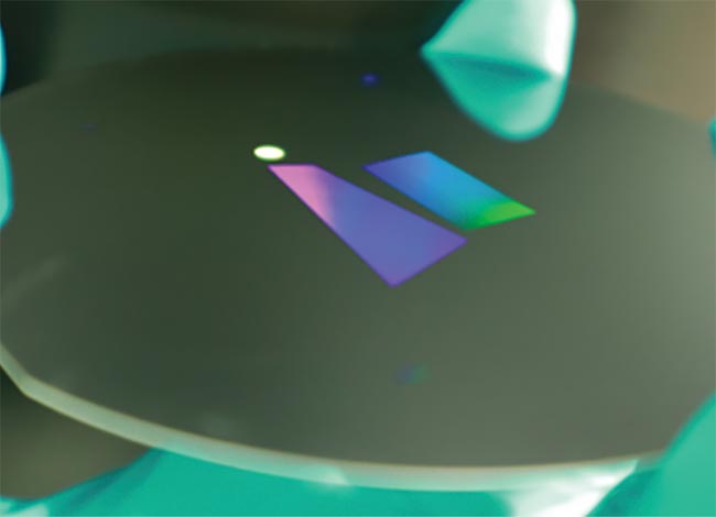An AR waveguide illuminated from the bottom. The circular port is where the overlay image from the light engine enters the waveguide. This overlay image is expanded in the trapezoidal section for an expanded eye-box and finally projected out of the plane of the waveguide into the users’ eyes. Courtesy of NIL Technology.