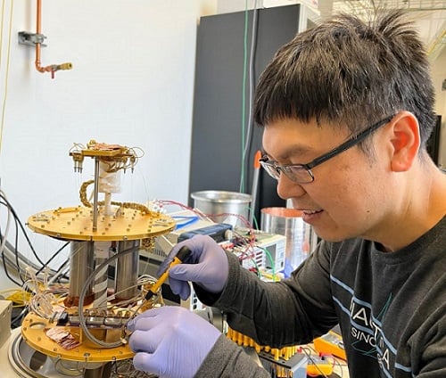 Fermilab scientist Si Xie mounts a superconducting nanowire single photon detector inside a cryostat. He and his colleagues will use the detector to look for light created by dark matter particles. Courtesy of Christina Wang/Fermilab.