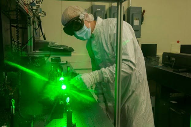Metrology technician making a high sensitivity photothermal CPI Absorption measurement to ensure optical coating process consistency and material conformance.