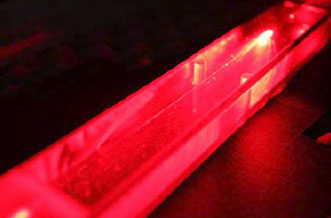 A red HeNe laser beam passes through a 1-micron optical fiber.
