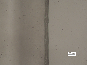 Top view of the edge of a 20-µm-thick polyethylene sheet (at left), cut using a 164-W CO laser at a feedrate of 3000 mm/s.