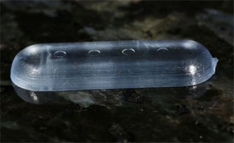 A plastic prototype pill with indentations of less than 0.5 mm, creating a 3D bar code.