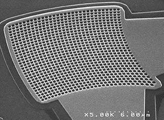 A surface grating coupler that couples light from a fiber sits atop a silicon photonics chip. 