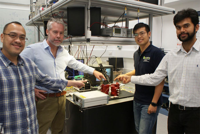 Researchers David Marpaung, Benjamin Eggleton, Yang Liu and Amol Choudhary pointing at a thumbnail-size chip being evaluated in the broadband microwave testbed, inside the Sydney Nanoscience Hub. Courtesy of University of Sydney.