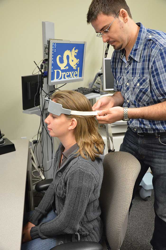 Hasan Ayaz placing a prefrontal fNIRS sensor band on a volunteer.