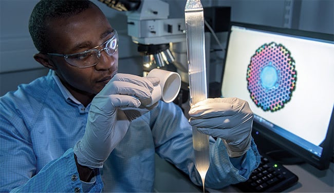 A researcher checks a microstructured fiber preform in the Optoelectronics Research Center at the University of Southampton. Courtesy of the Optoelectronics Research Center, University of Southampton.