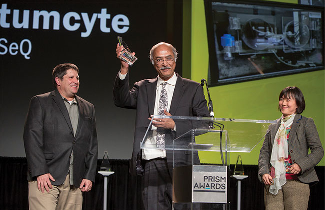 Bidhan Chaudhuri, founder and chief technology officer of QuantumCyte, accepts the 2018 Prism Award in the Life Science and Instrumentation category along with John Butler, CEO (left), and Bernadine Lim, vice president of international business development.
