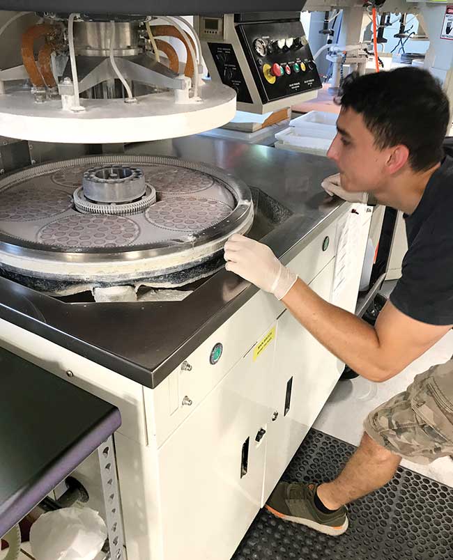 Logan Wickersham, of Esco Optics, prepares to unload a double-sided polishing machine. 