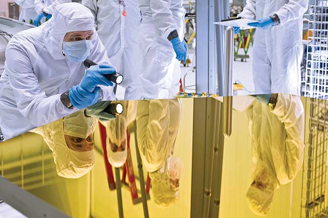 An engineer examines the Webb telescope primary mirror in the cleanroom at NASA’s Goddard Space Flight Center, Greenbelt, Md.