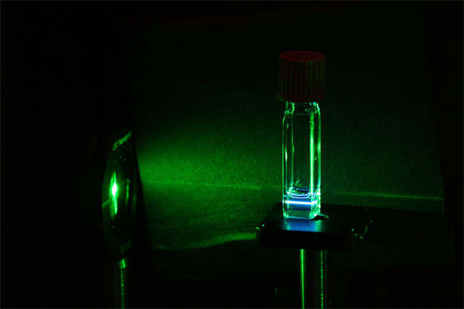 A green lower-energy laser light goes through silicon quantum dots. The quantum dots re-emit, or upconvert, the low-energy light into a higher-energy blue light. Courtesy of Lorenzo Mangolini and Ming Lee Tang/UCR.
