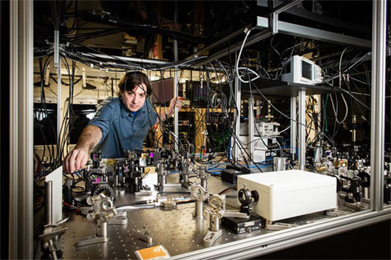 Quantum Back Action Measurement Could Improve Sensitivity of Gravitational-Wave Detectors  BATON ROUGE, La., March x, 2019 &mdash; Researchers at Louisiana State University (LSU) have defined a broadband, off-resonance measurement of quantum radiation pressure noise (QRPN) in the audio band, at frequencies relevant to gravitational wave detectors. The noise spectrum obtained by the team shows effects due to QRPN between about 2 kilohertz and 100 kilohertz. The results of the research could lead to methods to improve the sensitivity of gravitational-wave detectors by developing techniques to mitigate the imprecision in back action measurements, thus increasing the chances of detecting gravitational waves. The researchers developed devices, housed in miniature models of detectors like LIGO, that made it possible to observe quantum effects at room temperature. The devices consist of low-loss, single-crystal microresonators. Each mirror pad is the size of a pin prick and is suspended from a cantilever. When a laser beam is directed at one of the mirrors, the beam that is reflected causes enough fluctuating radiation pressure to bend the cantilever structure, causing the mirror pad to vibrate and create noise. Gravitational wave interferometers use high-power lasers in order to minimize the uncertainty caused by the measurement of discrete photons and maximize the signal-to-noise ratio. These high-power beams increase position accuracy but do so at the expense of back action in the form of QRPN. Advanced LIGO and other second and third generation interferometers will be limited by QRPN at low frequencies when running at their full laser power; but the LSU team, which includes collaborators at MIT, offers clues as to how scientists can work around this when measuring gravitational waves. “Given the imperative for more sensitive gravitational wave detectors, it is important to study the effects of quantum radiation pressure noise in a system similar to Advanced LIGO, which will be limited by quantum radiation pressure noise across a wide range of frequencies far from the mechanical resonance frequency of the test mass suspension,” said professor Thomas Corbitt. Proposals to improve the sensitivity of gravitational-wave detectors exist; but until now, said the researchers, no platform has allowed for experimental tests of these ideas.  “This breakthrough opens new opportunities for testing noise reduction,” said Pedro Marronetti, a physicist and National Science Foundation program director. “The relative simplicity of the approach makes it accessible by a wide range of research groups, potentially increasing participation from the broader scientific community in gravitational wave astrophysics.” The research was published in <I>Nature</I> (https://doi.org/10.1038/s41586-019-1051-4). https://www.nature.com/articles/s41586-019-1051-4 kw: research & technology, education, Louisiana State University, LIGO, gravitational wave detector, metrology, lasers, Americas, optics, quantum, sensors & detectors, astronomy, quantum optics, single photons, quantum metrology CAPTION 1 LSU Department of Physics & Astronomy associate professor Thomas Corbitt and his team present a broadband, off-resonance measurement of quantum radiation pressure noise in the audio band, at frequencies relevant to gravitational wave detectors. Courtesy of Elsa Hahne, LSU.  Professor Thomas Corbitt in his lab, setting up a complex sequence of lasers. Courtesy of Elsa Hahne, LSU.