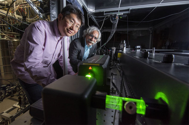 Professor V. Ara Apkarian (r), director of UCI’s Center for Chemistry at the Space-Time Limit (CaSTL) and researcher scientist Joonhee Lee stand over the femtosecond titanium sapphire laser used in their experiments. The machine in the background is CaSTL’s ultra-high-vacuum cryogenic scanning tunneling microscope. Courtesy of Steve Zylius/UCI.