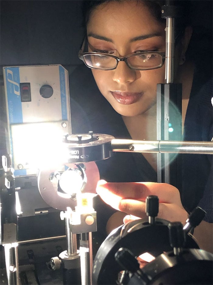 McMaster researcher Fariha Mahmood uses new computing technology by shining patterned bands of light through a polymer cube. Courtesy of McMaster University.