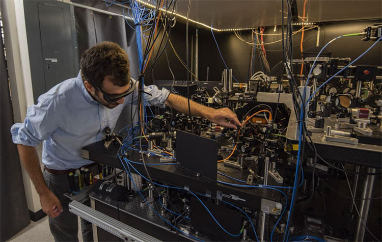 NIST researchers develop atomic clock design that uses laser tweezers to control atoms. Pictured, physicist Adam Kaufman.