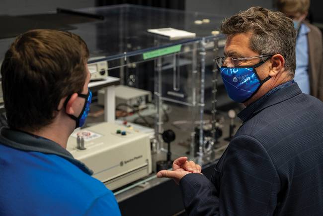 A student and Photonics North 2022 attendee in the class IV laser lab featuring a Ti:Sapphire laser in the background. Courtesy of LASER-TEC.