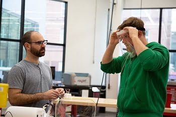 Justin Suriano and Daniel Brateris try on a face shield they designed and fabricated in the Makerspace at NJIT. Courtesy of NJIT.