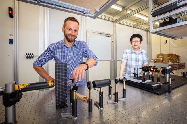 With their international colleagues, professor Dmitry Turchinovich (l) and researcher Wentao Zhang (r) demonstrate how the ultrafast change of magnetic states can be measured. Courtesy of Bielefeld University/M.D. Müller.