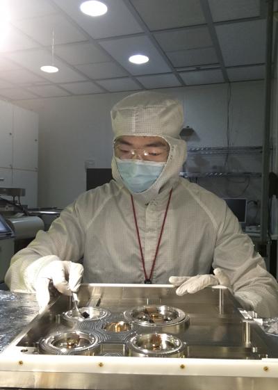 Lead author Mingxiao Li holds a small lithium niobate chip in an etching chamber. Courtesy of the laboratory of Qiang Lin/University of Rochester.