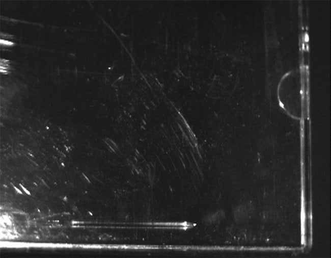 Faint scratches on glass and plastic are often much more apparent when imaged under UV light. This is evident in these two images of a CD jewel case captured with a visible-range sensor (top) and a UV camera (bottom). Courtesy of Oculus Photonics.