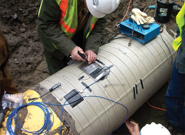 Installation of fiber optic Bragg gratings designed for a preexisting oil pipeline buried along the Hood River in Washington state. Fiber optic sensors can help to monitor temperature, excess strain, and bending of pipelines caused by movement of soil around buried pipelines. Courtesy of Redondo Optics.