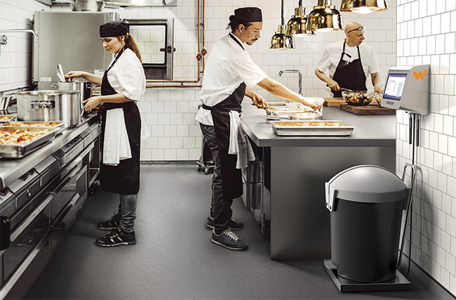 The Winnow Vision system, mounted on a wall above a bin (right) in a restaurant kitchen, classifies food waste and helps to reduce it by as much as 50%. Courtesy of Winnow.
