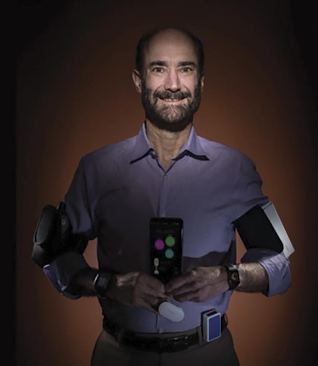 Stanford University professor Michael Snyder displays some of the wearable technologies he has been using to monitor his health, some of which helped him to detect Lyme disease at an early stage. Courtesy of Steve Fisch Photography/ Stanford Medicine.