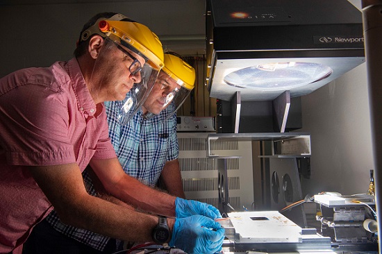 Joshua Stein, front, a Sandia National Laboratories engineer and director of a new Perovskite Photovoltaic Accelerator for Commercializing Technologies Center, and Charles Robinson, a Sandia technologist, examine a solar module. The new center will determine the best performance and reliability tests for perovskite solar modules. Courtesy of Randy Montoya/Sandia National Laboratories
