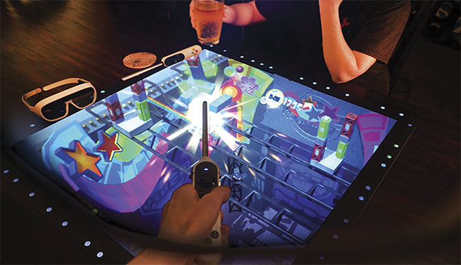 An interactive game board as seen through AR glasses. Patterned light projected from the glasses bounces off the board, which acts as a retroreflector, to enable users to perceive a virtual image on the physical board. Courtesy of Tilt Five.
