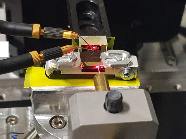 The experimental setup for the compact Fourier-transform waveguide spectrometer, which, according to its designers and developers, will allow optical measurement instruments to be integrated consumer electronics and ultrasmall satellites. The team used a red alignment laser to visualize the beam path from the fiber into the optical waveguide and its reflection at a gold mirror. Two microprobes were used to contact the photoconductor, the size of which is in the subwavelength range. Courtesy of Empa.