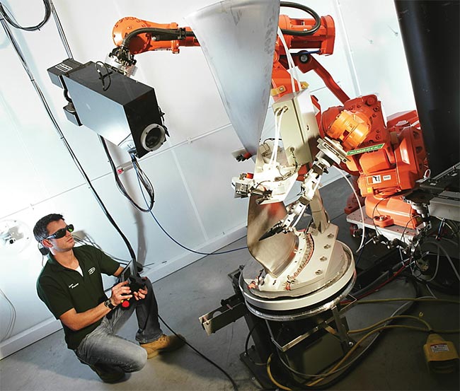 An operator laser peens a large blade for a Rolls-Royce jet engine, selectively creating areas of compressive stress to enhance the blade’s resistance to fatigue and cracking. Courtesy of Curtiss-Wright.