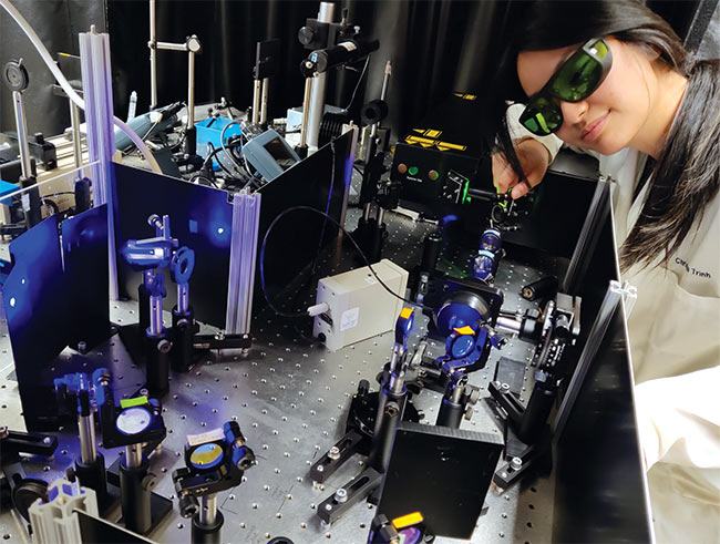 University of California, San Diego graduate student Christina Trinh uses UV resonance Raman spectroscopy to analyze unnatural amino acids in an electron transfer protein. Courtesy of University of California, San Diego/Judy Kim.