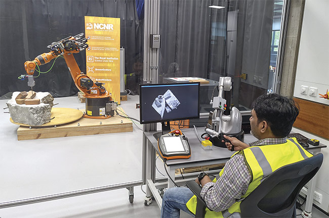 In the experimental setup, 3D point cloud images of the objects are shown on a screen. A tactile haptic feedback device helps the operator guide the robot arm in correct movement. Courtesy of Naresh Marturi, Extreme Robotics Laboratory/National Centre for Nuclear Robotics, University of Birmingham.