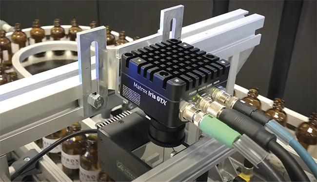  In a setup combining traditional machine vision and deep learning, a smart camera inspects the lips of glass bottles and spots hard-to-detect defects. Advancements make it possible for the edge IoT device to run the needed advanced analytics. Courtesy of Matrox Imaging.