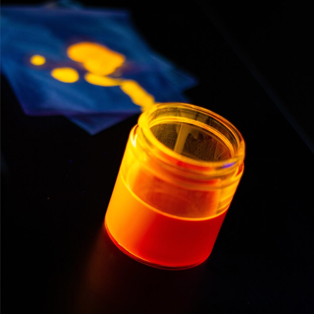 A quantum dot ink solution emitting an orange glow under ultraviolet excitation. Courtesy of UbiQD, Inc.