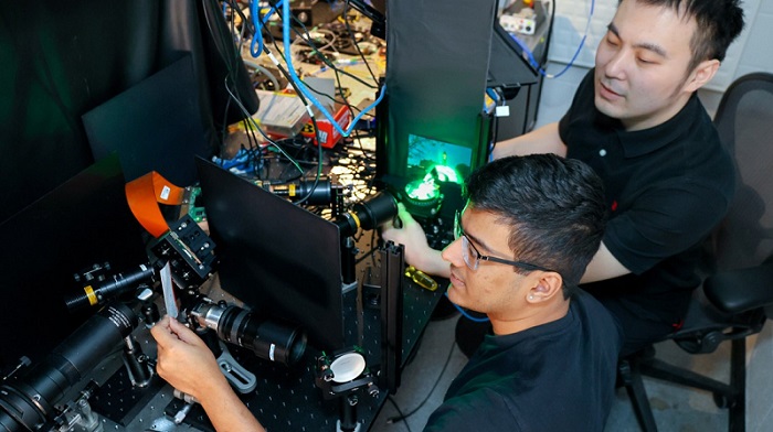 Doctoral student Mandar Sohoni, left, and postdoctoral researcher Tianyu Wang adjust their research setup that tests the ability of an optical neural network to measure objects in a 3D scene. Courtesy of Charissa King-O’Brien.