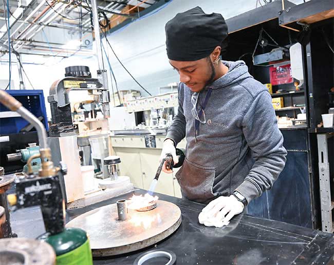 In Ontario, New York, an East High School optics program graduate works with one of Optimax’s spherical manufacturing cells. Courtesy of Optimax.