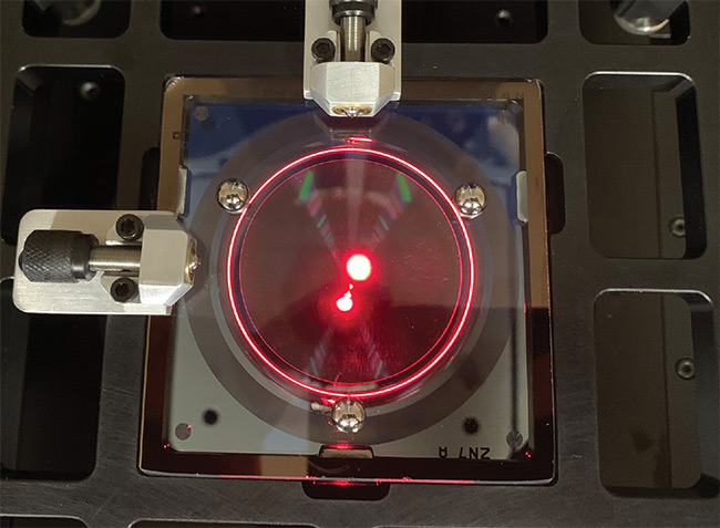 A computer-generated hologram (CGH) for testing aspheric optics with direct-mount features and a laser interferometer shining a test beam through it. Courtesy of Arizona Optical Metrology.