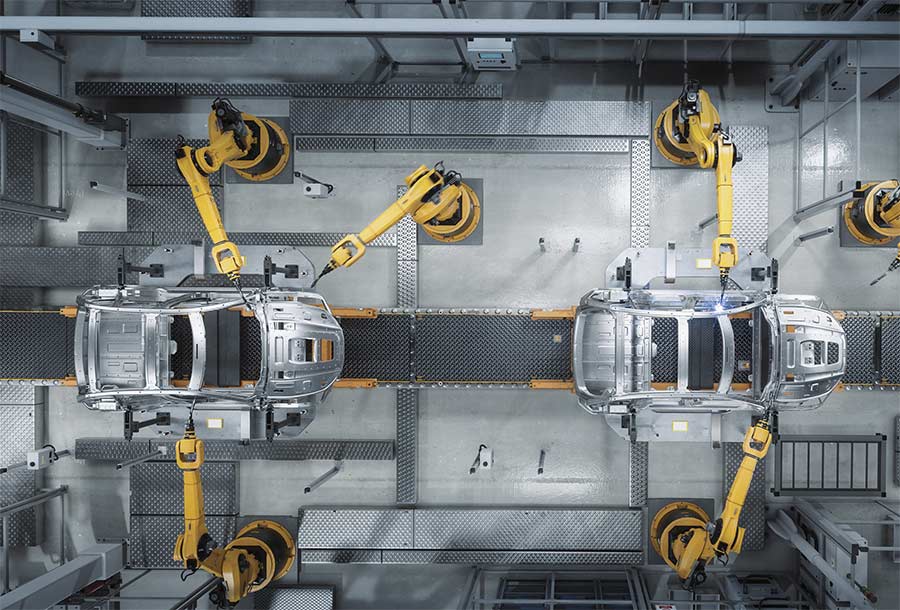 An aerial view of an automated robot arm assembly line manufacturing advanced, high-tech green energy electric vehicles. Courtesy of iStock.com/gorodenkoff.