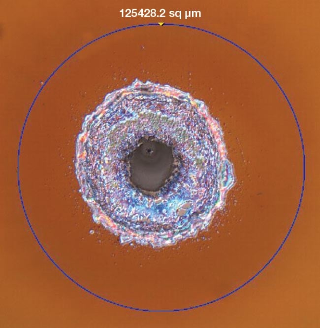 High-power laser systems are increasingly susceptible to laser-induced damage, such as the damage on a glass surface, captured here using differential interference contrast microscopy. Courtesy of Edmund Optics.