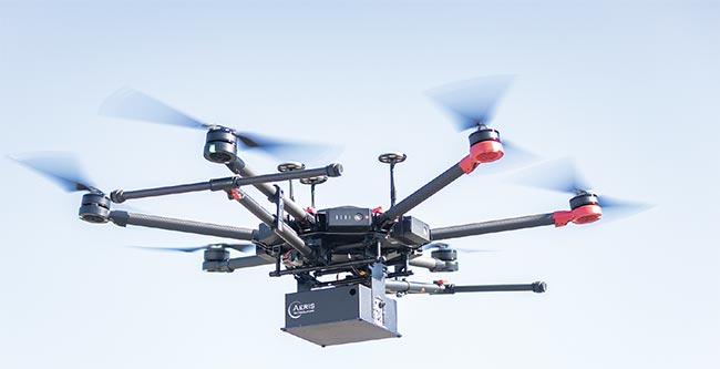 A drone equipped with a compact MIR gas analysis system flies overhead. Aeris incorporated a quantum cascade laser (QCL) into the system to probe the MIR region for the presence of analytes in the atmosphere. Courtesy of Aeris.